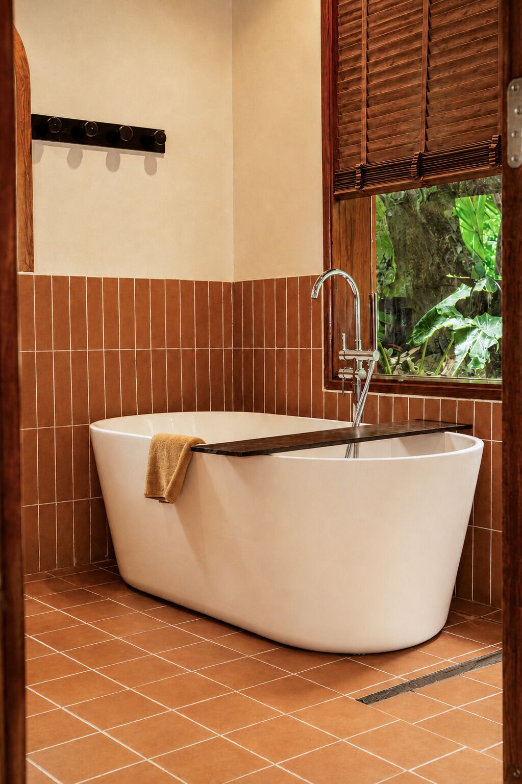 Eine freistehende Badewanne in einem Badezimmer mit Blick durch ein Fenster auf Grünflächen.
