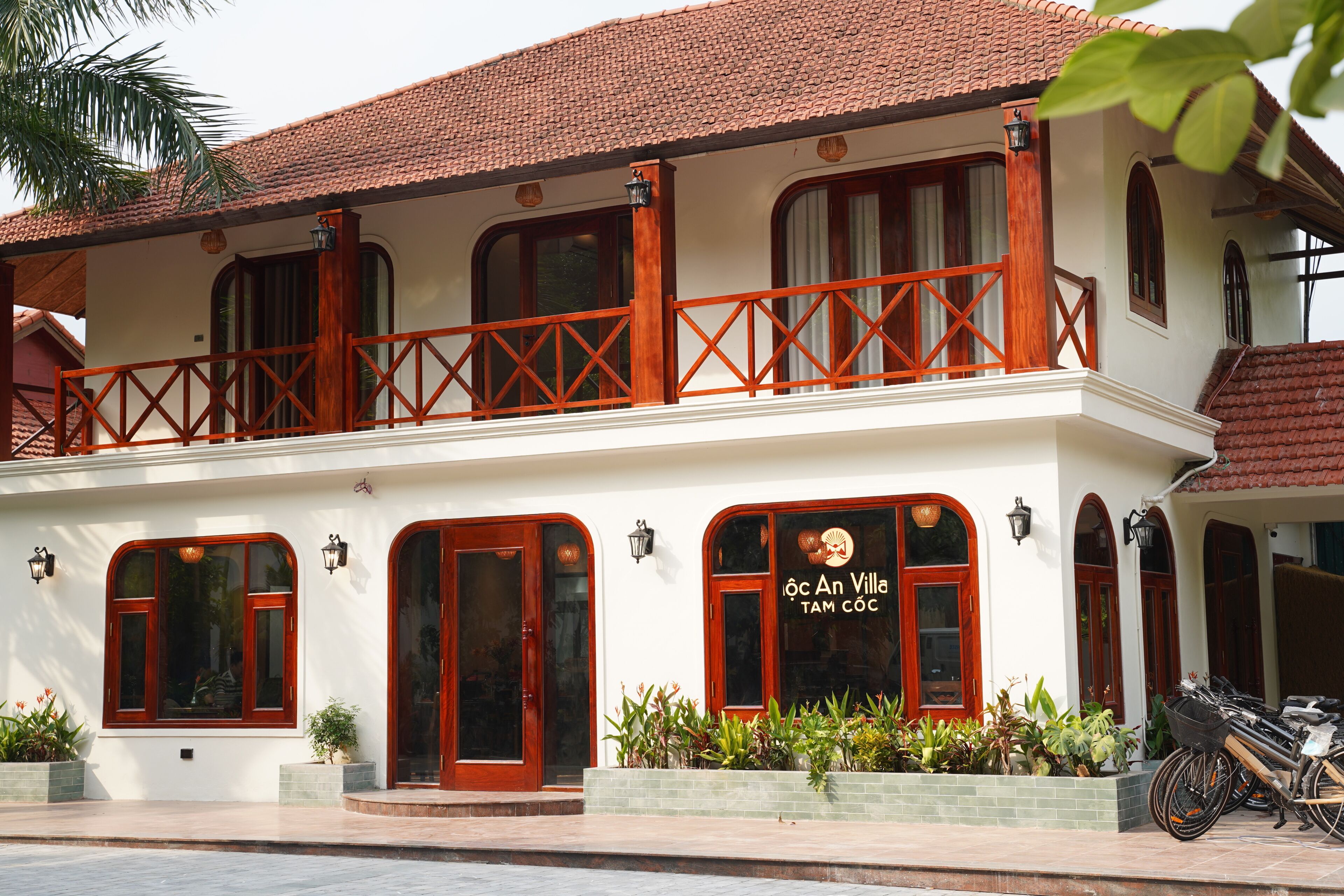 A two-story building with a balcony, large windows, and a sign that reads 'OCA An Villa TAM COC'.