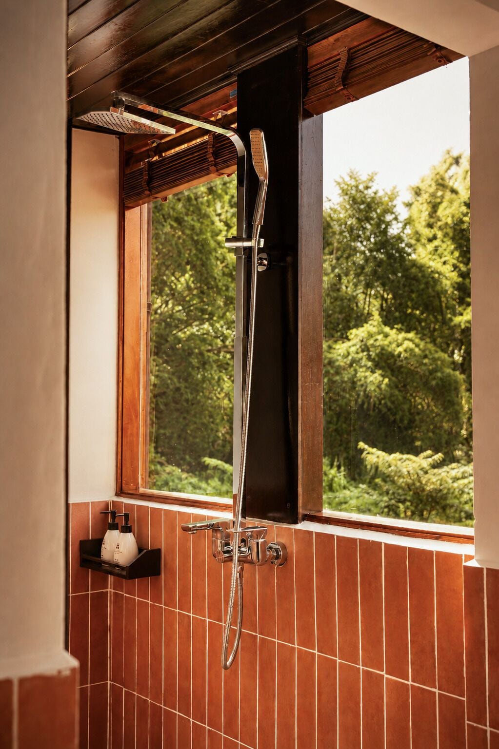 A shower with a rain showerhead, a handheld showerhead, and a wall-mounted faucet.
