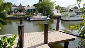 Un muelle con barcos, una estructura de techo de paja y un edificio con techo azul.