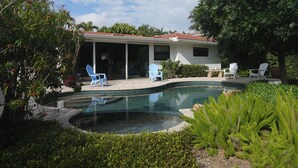 Una casa con piscina, mobiliario de exterior y un porche cubierto.