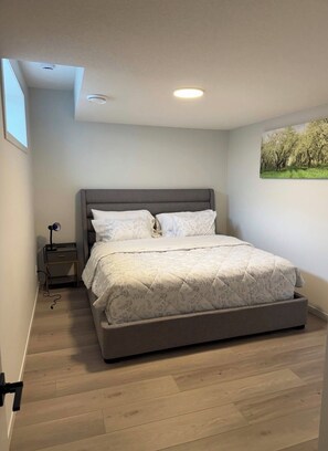 Une chambre à coucher avec un lit, une table de chevet, une lampe et un tableau au mur.