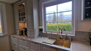 A kitchen with a large window, a sink, and a countertop.