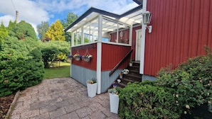 A red building with a covered porch, a staircase, and potted plants.