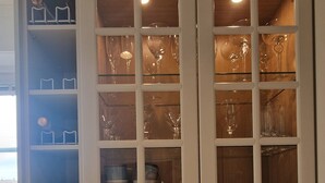 A kitchen with marble countertops, a coffee maker, a bottle of champagne, and a vase with a flower.