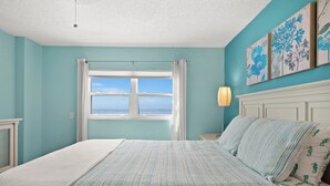 Une chambre à coucher avec un lit, une fenêtre avec des rideaux, une table de chevet et une lampe fixée au mur.