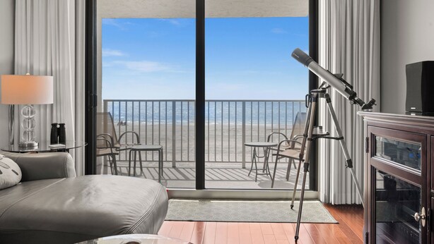 Une chambre d’hôtel avec un balcon, un lit, un bureau et un télescope.