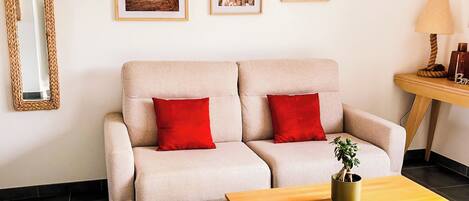 A modern living room with a sofa, a coffee table, a wicker chair, and a lamp.