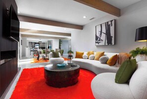 A modern living room with a sectional sofa, a coffee table, and a red rug. - Palm Springs 4BR | King Beds, Private Pool (Palm Springs)