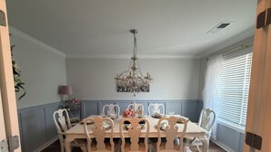 A dining room with a chandelier, white chairs, a table set for six, and a blue patterned rug. - The Masters 2027 Rental: Coming Soon! (Lexington)