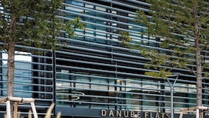 A modern building with the name 'DANUBE FLATS' on its facade, surrounded by a garden with various flowers. - Skyline Suite - Danube-View Balcony&Pool (Vienna)