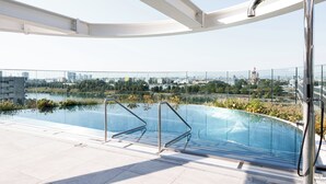 An outdoor infinity pool with metal railings, a city view, and a clear sky. - Skyline Suite - Danube-View Balcony&Pool (Vienna)