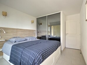 Une chambre à coucher avec un lit, des tables de chevet, une armoire et une porte.