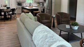 Eine moderne Küche mit weißen Schränken, Edelstahlgeräten und einem Essbereich mit einer Couch und Stühlen.