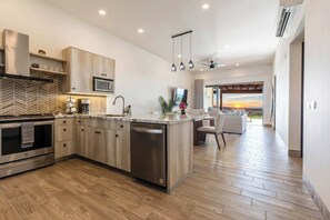 A modern kitchen with a central island, stainless steel appliances, and a herringbone-patterned backsplash. - Modern luxury & unforgettable sunsets at Mavila - huge patio w pool (Cabo San Lucas)