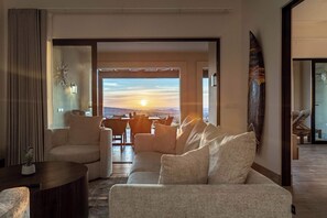 A modern living room with a sofa, armchairs, a coffee table, and a dining area with chairs. - Modern luxury & unforgettable sunsets at Mavila - huge patio w pool (Cabo San Lucas)