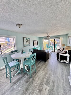 A spacious room with a dining table, chairs, a sofa, and a ceiling fan. - Incredible Beach Villa 1bd/1ba Myrtle Beach (Myrtle Beach)