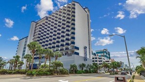 A hotel with a checkered facade, palm trees, and a clear blue sky. - Incredible Beach Villa 1bd/1ba Myrtle Beach (Myrtle Beach)