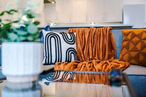 Una sala de estar moderna con un sofá, cojines estampados y una mesa de centro de vidrio.