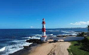 Eine Küstenlandschaft mit einem Leuchtturm, einem Sandstrand und dem Meer.