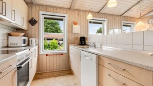 Eine kleine Küche mit Holzwänden, einem Fenster und modernen Geräten.