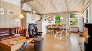 Ein gemütliches Wohnzimmer mit Ledersofa, Couchtisch aus Holz und Essbereich mit Holzsesseln und Tisch.