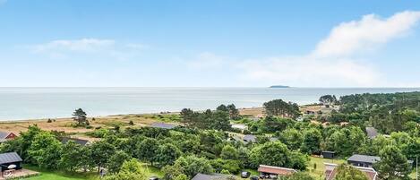 A residential area with houses, a grassy field, and a body of water in the background.
