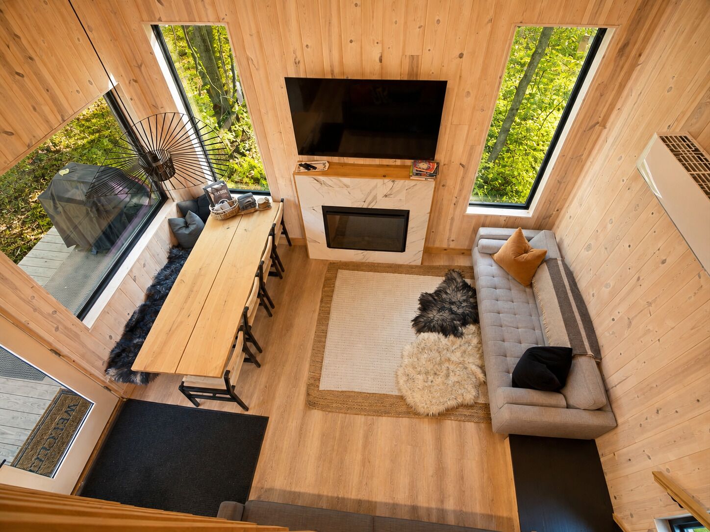 A cozy cabin interior with a wooden dining table, sofa, and a flat-screen TV.