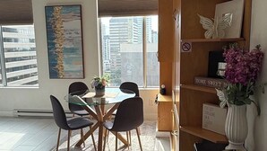 Ett modernt matområde med ett glasbord och stolar, en dekorativ matta och en bokhylla med en skylt.