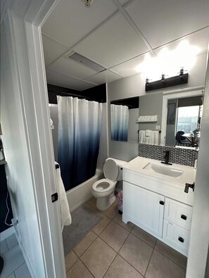 A bathroom with a toilet, sink, and shower curtain. - High rise Exquisite Comfortable Loft (Edmonton)