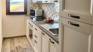 Uma cozinha com armários brancos, micro-ondas, pia e janela com vista.