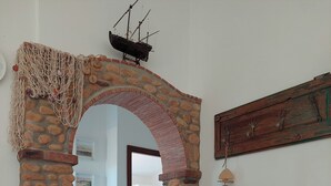 Uma porta de pedra arqueada que dá para um quarto com uma cama e uma decoração de peixe pendurado.