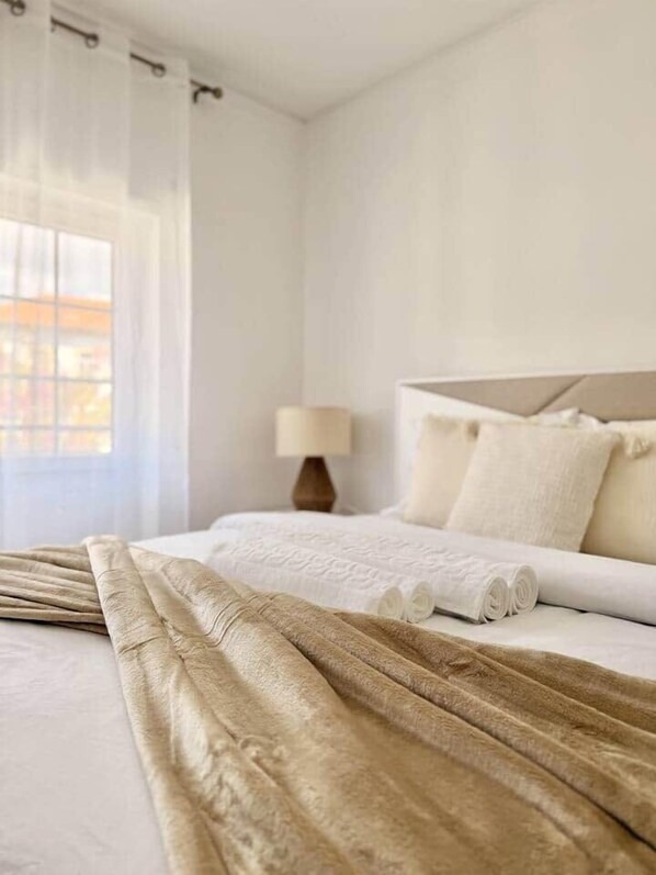 A hotel room with a bed, a lamp, and a view through the window.
