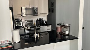 A modern kitchen with stainless steel appliances, a black countertop, and white cabinetry. - Industrial Tech Loft in Atlanta (Atlanta)