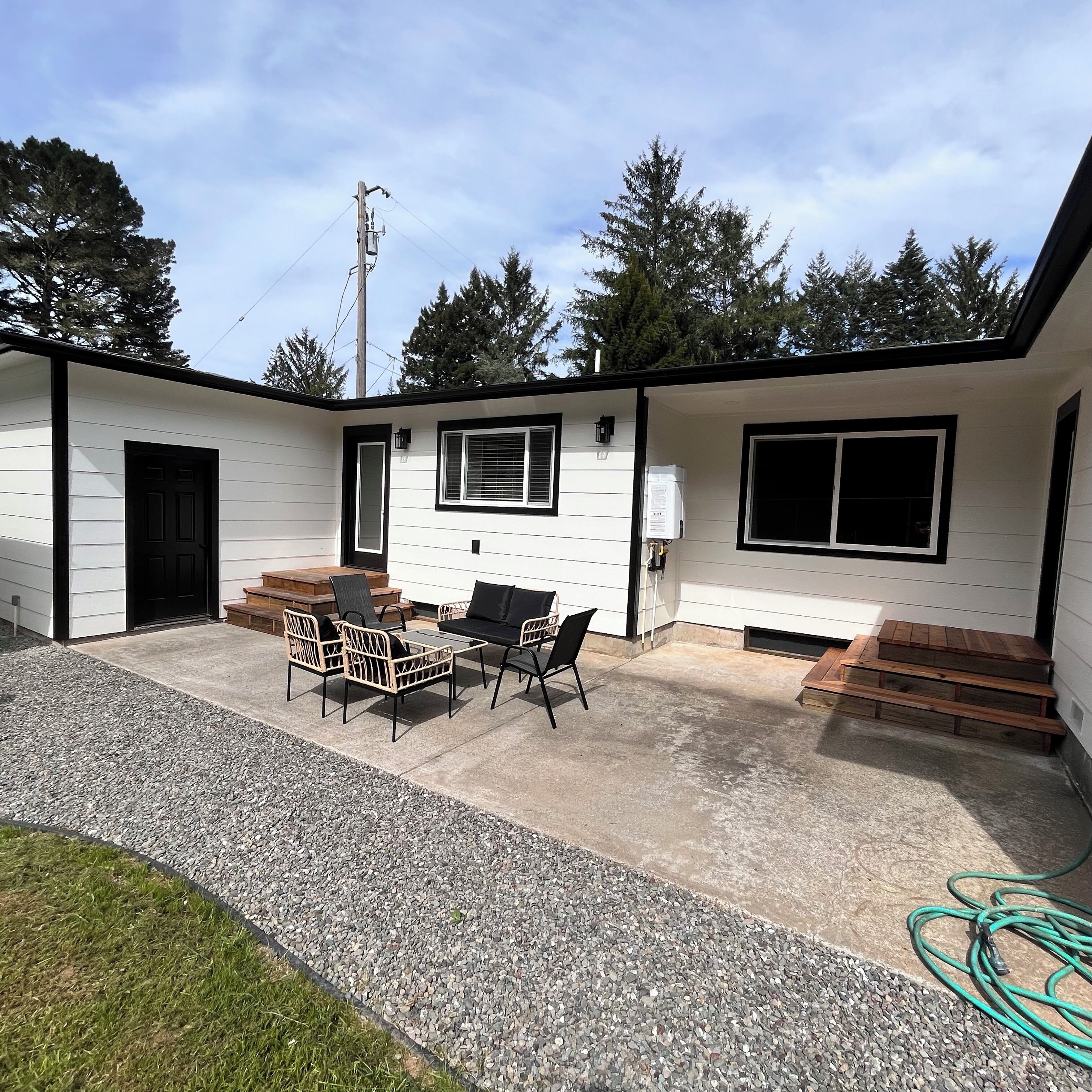 A single-story building with a patio area featuring outdoor furniture and a water heater.