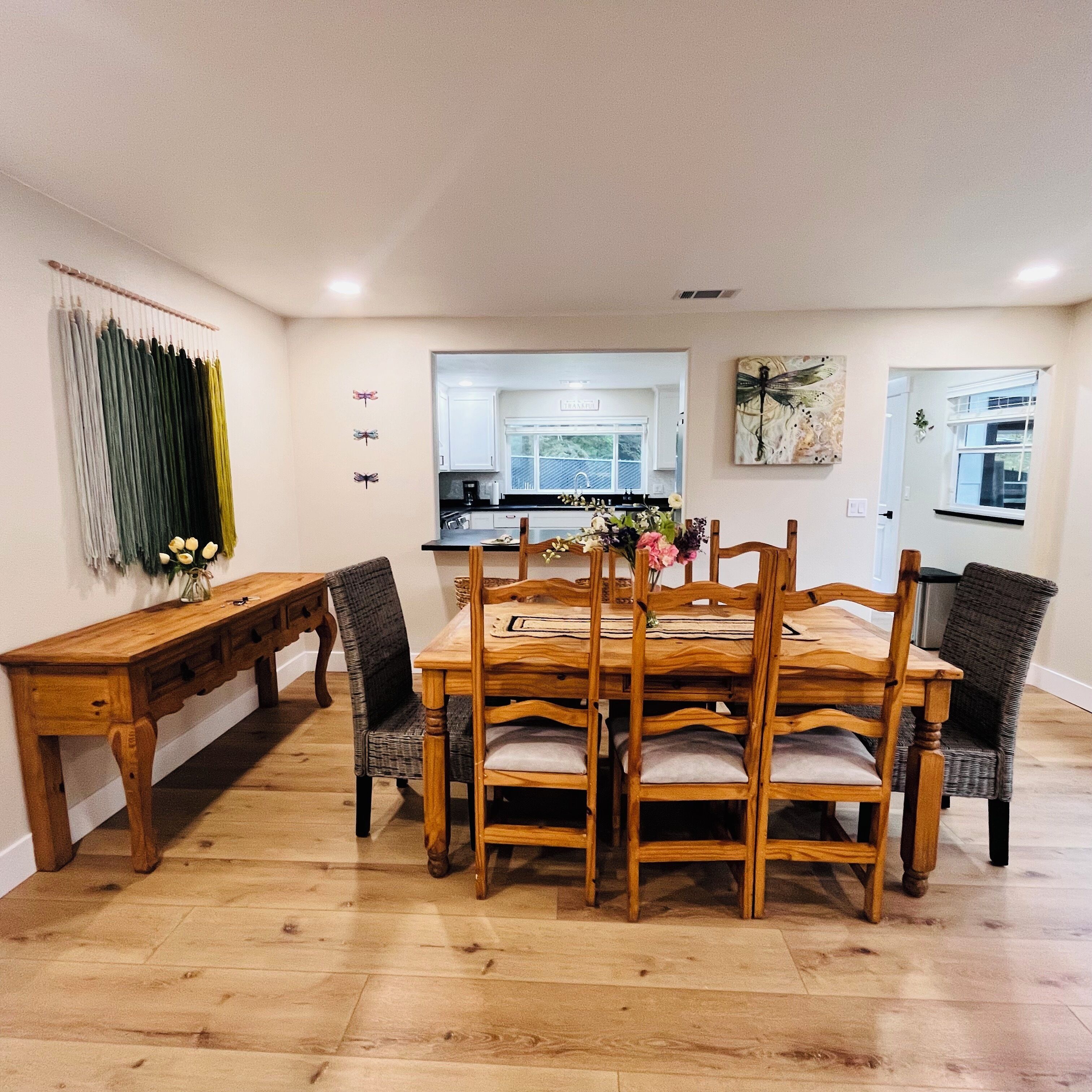 Un comedor con una mesa y sillas de madera, un banco y una cocina al fondo.