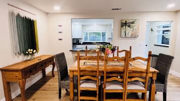 Un comedor con una mesa y sillas de madera, un banco y una cocina al fondo.