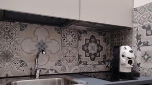 A kitchen with a stainless steel sink, a coffee maker, and patterned backsplash tiles. - B&B Al Teatro Romano (Benevento)