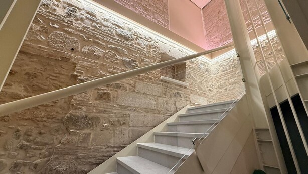 A staircase with a stone wall backdrop, a handrail, and a view of the upper floor. - B&B Al Teatro Romano (Benevento)