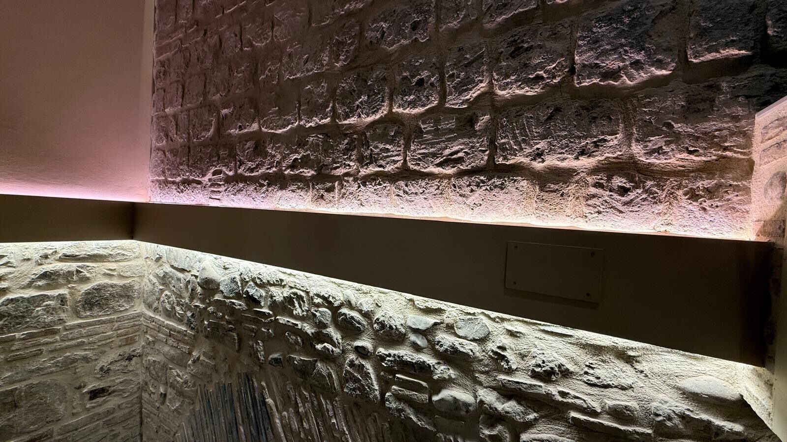 Paret de pedra amb textura, amb una zona escotada i una superfície plana de pedra.