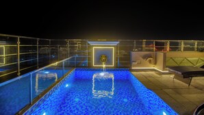 Piscina no terraço com barreira de vidro, um elemento central de água e área de estar.