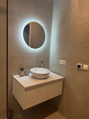 A bathroom with a round mirror, a vessel sink, and a cabinet. - Tante Ursula B&B (Venlo)