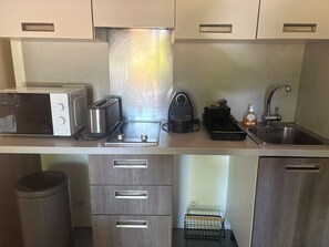 Eine Küchenzeile mit Mikrowelle, Toaster, Wasserkocher, Spüle und Stauraum.