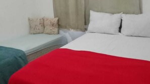 Una habitación con una cama, una mesita y una ventana con cortinas.