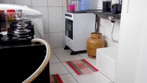 Una cocina con estufa a gas, horno blanco, cilindro de gas y un tapete a rayas.