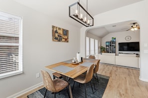 A dining area with a wooden table, chairs, and a chandelier.
