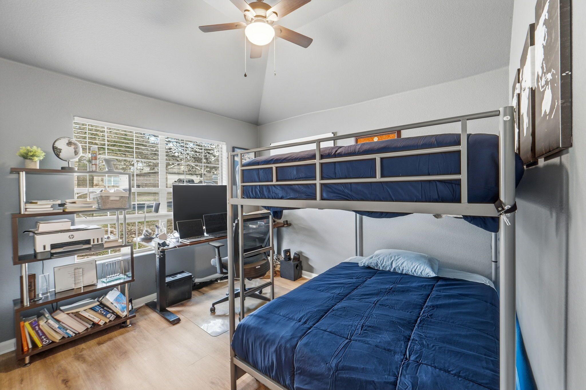 Une chambre avec un lit superposé, un bureau, un ordinateur et des étagères.