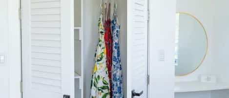 Un placard blanc avec une tringle pour suspendre les vêtements et un miroir sur le mur.