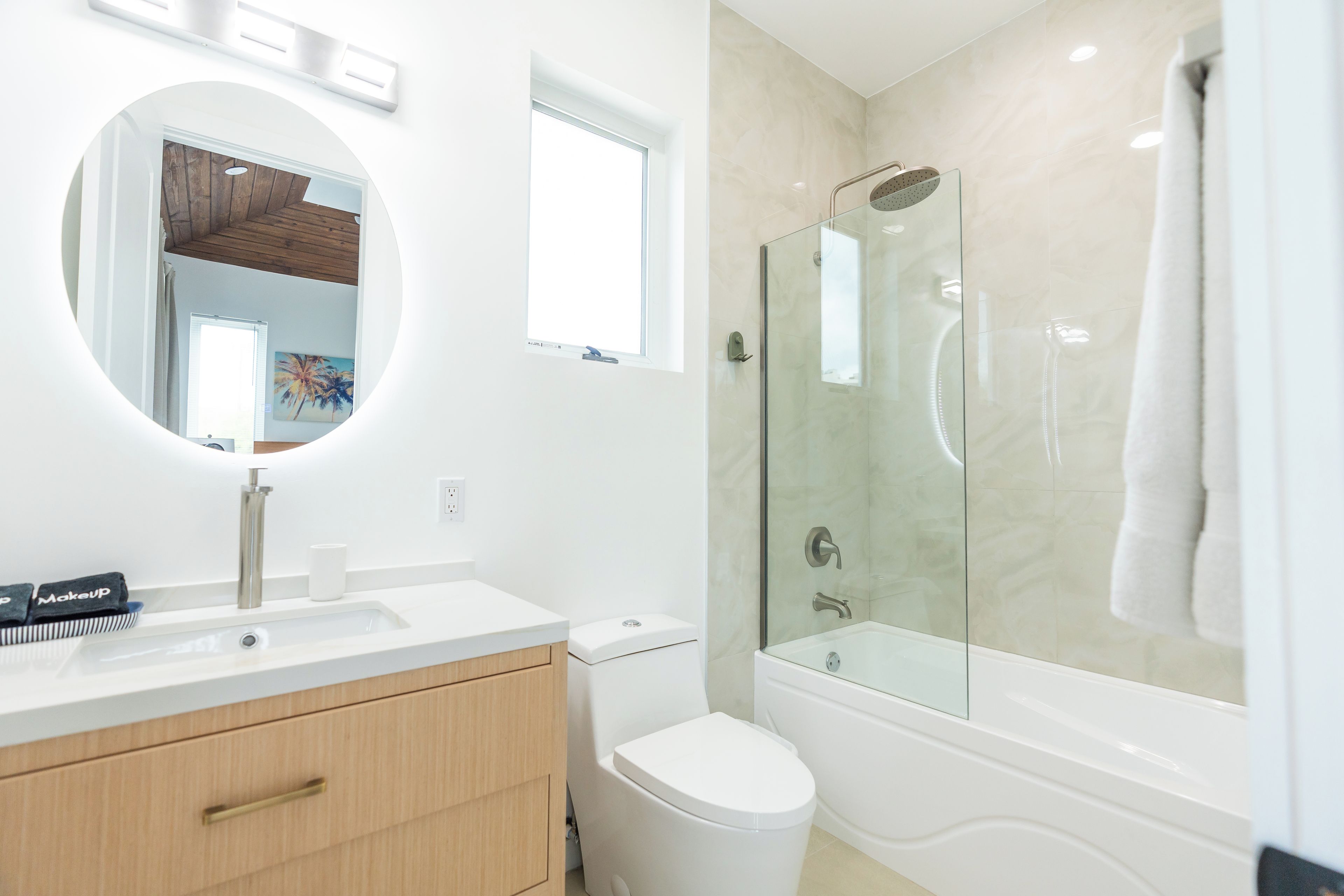 A modern bathroom with a white vanity, a glass shower enclosure, and a toilet.