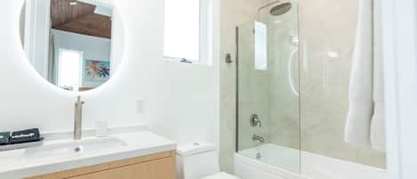 Une salle de bain moderne avec un meuble-lavabo blanc, une douche en verre et des toilettes.